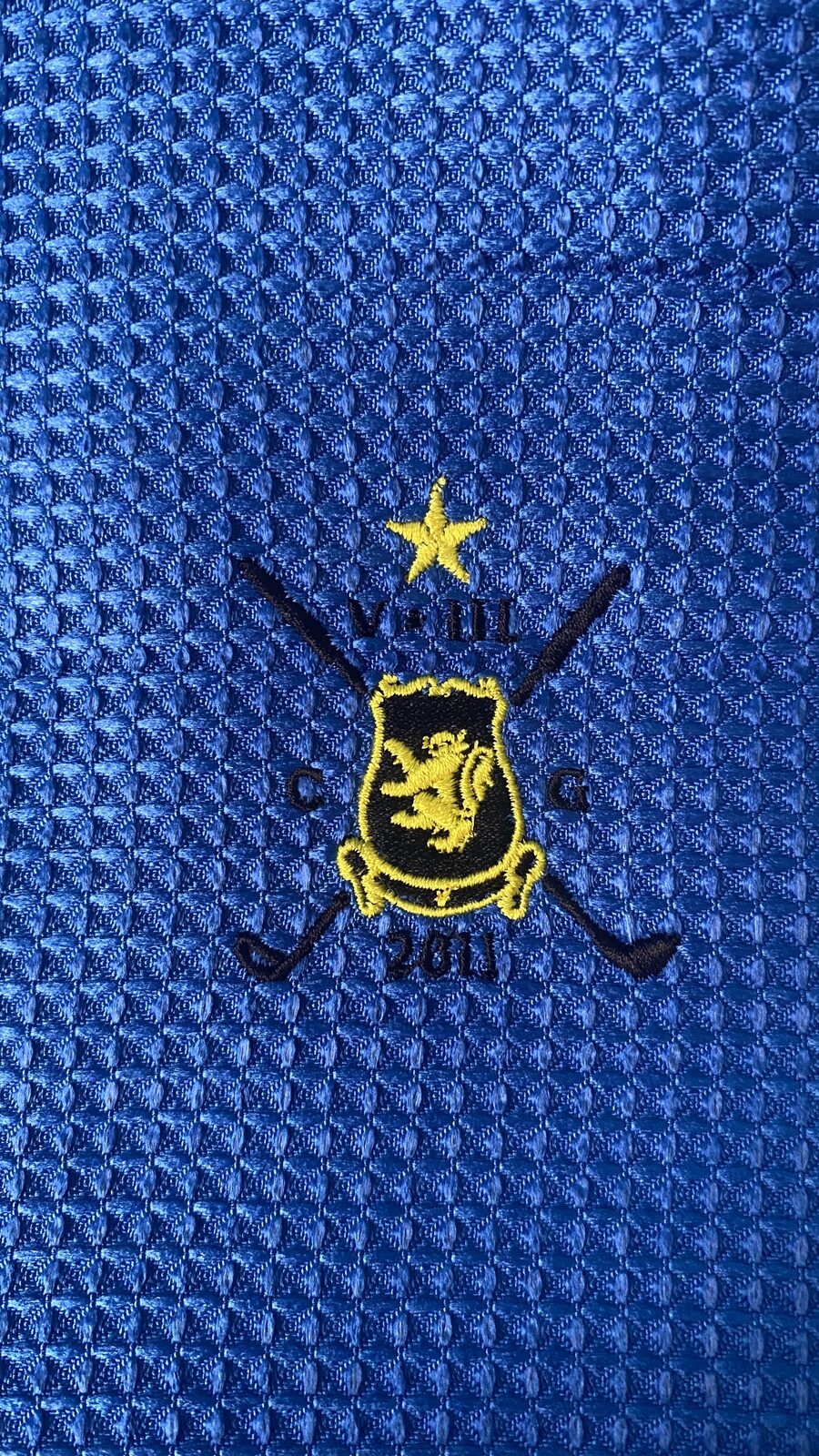 Detalle del bordado del escudo del Club de Golf 5 y 3 en una toalla azul